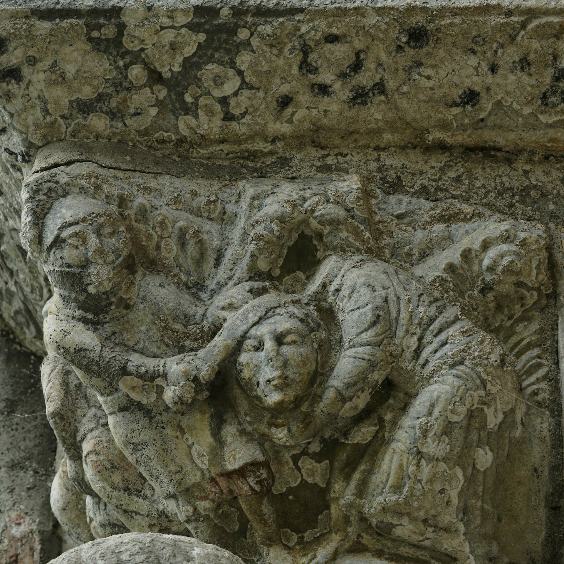 Weathered medieval stone carving of two figures — imagery of enduring record